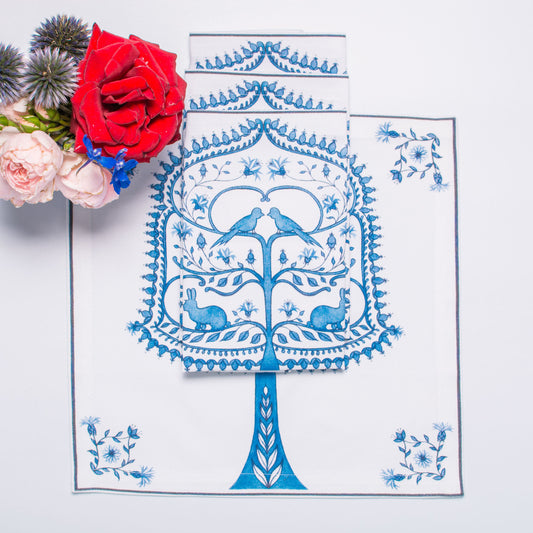 Decorative cotton napkin with blue tree design on a white surface with flowers.