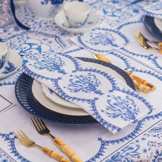 Table setting with blue and white patterned tablecloth, plates, and cutlery.
