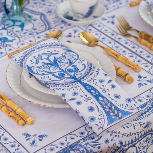 Table setting with blue and white patterned tablecloth, plates, and cutlery.