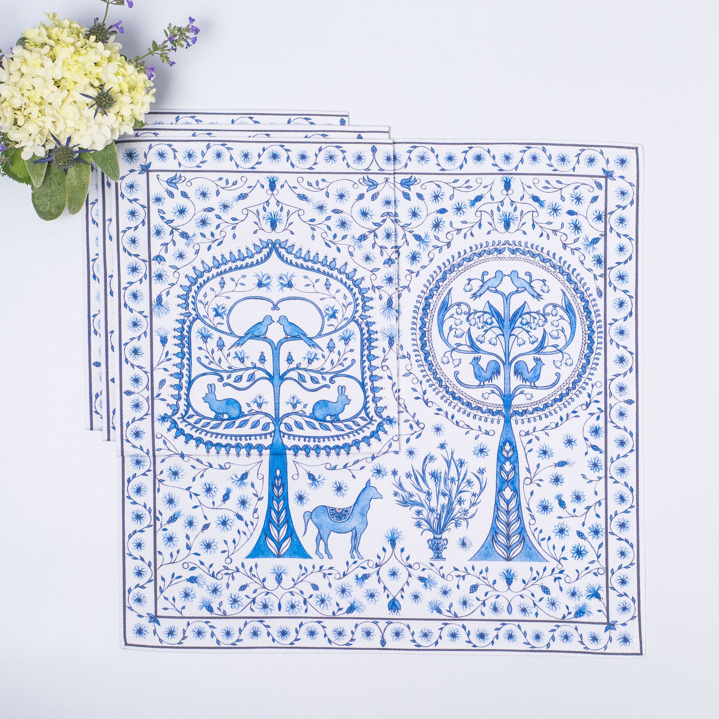 Set of blue and white patterned placemats with floral arrangement on light blue background