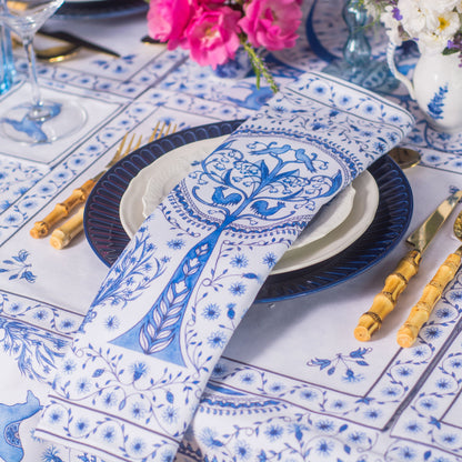 Table setting with blue and white patterned tablecloth, plates, and cutlery.