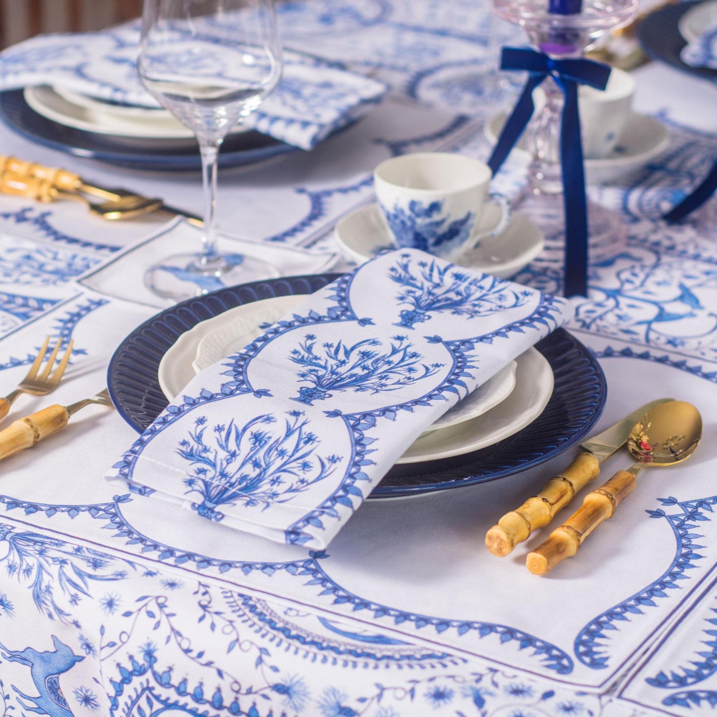 Table setting with blue and white tablecloth, napkins, plates, and cutlery.