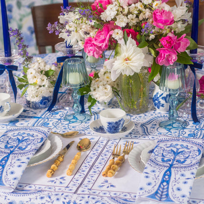 Decorative table setting with floral arrangements, blue and white tablecloth, and elegant cutlery.