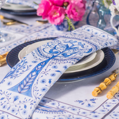 Elegant table setting with blue and white plates, napkins, and yellow cutlery on a white tablecloth.